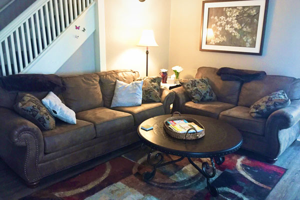 Brown couches and a round coffee table in a common room inside MHAST's Crisis Respite Supportive Residence